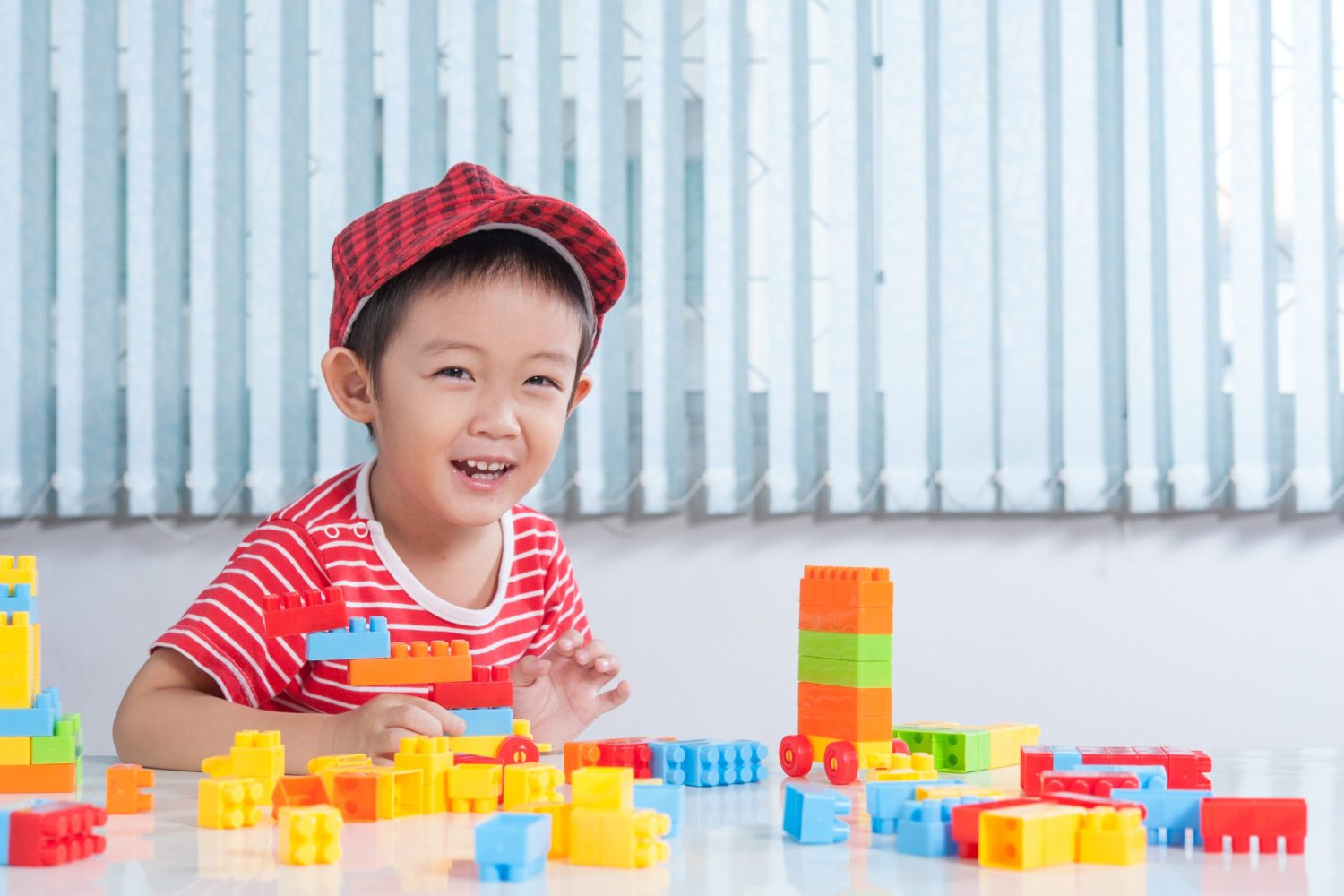 Asian Cute boy happy and playing with colorful plastic bricks at the table in the children's room